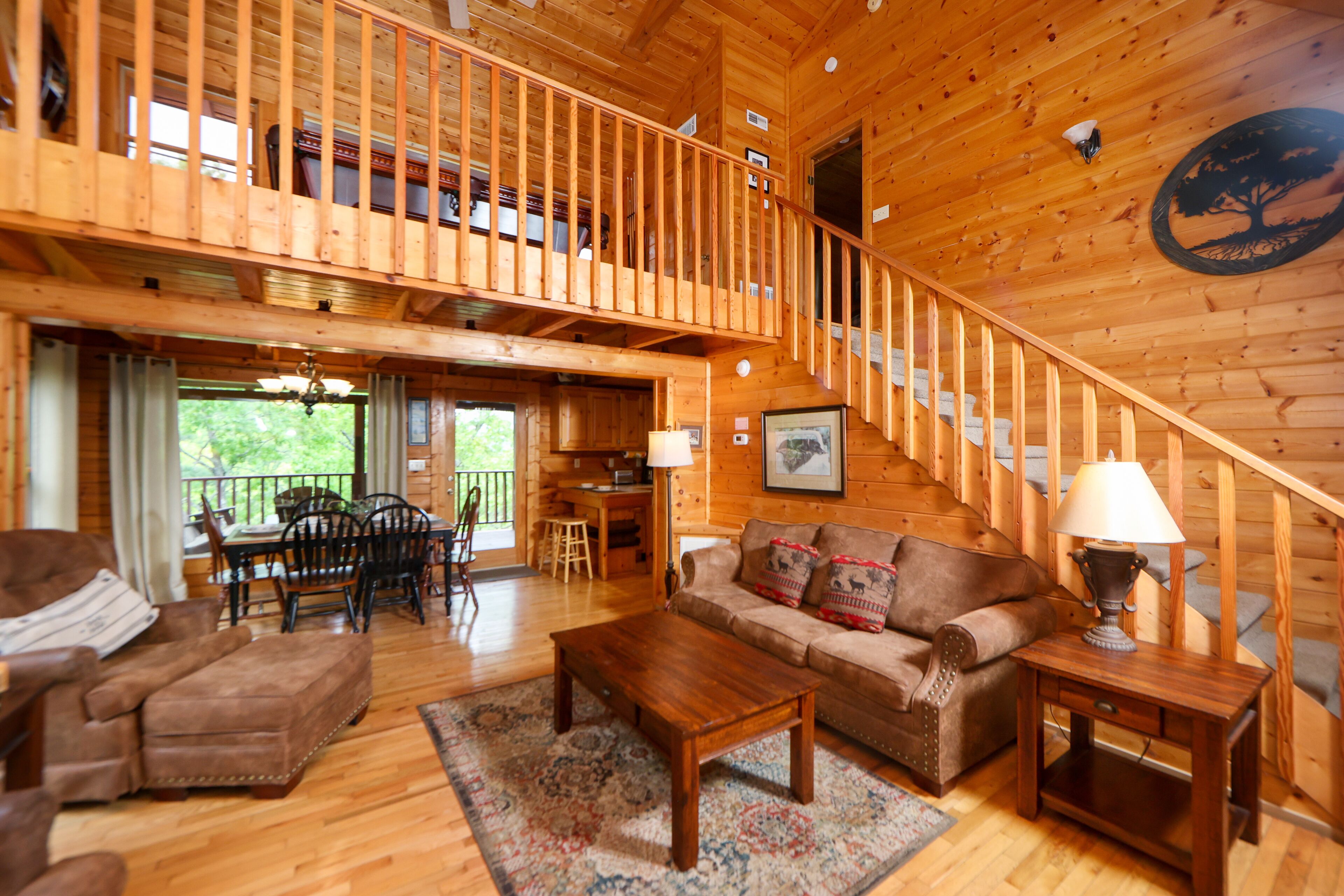 A wooden interior with a staircase, a sofa, a coffee table, and a dining area.