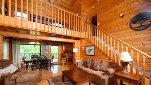 A wooden interior with a staircase, a sofa, a coffee table, and a dining area. - Beautiful Mountain View Overlooking The Smokies! Hot Tub, Pool Table, Mini Golf (Sevierville)