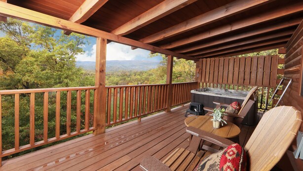 A wooden deck with a wooden railing, a table with chairs, and a barbecue grill. - Beautiful Mountain View Overlooking The Smokies! Hot Tub, Pool Table, Mini Golf (Sevierville)