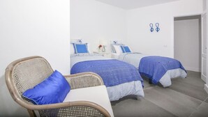 A room with two beds, a chair, and a door.