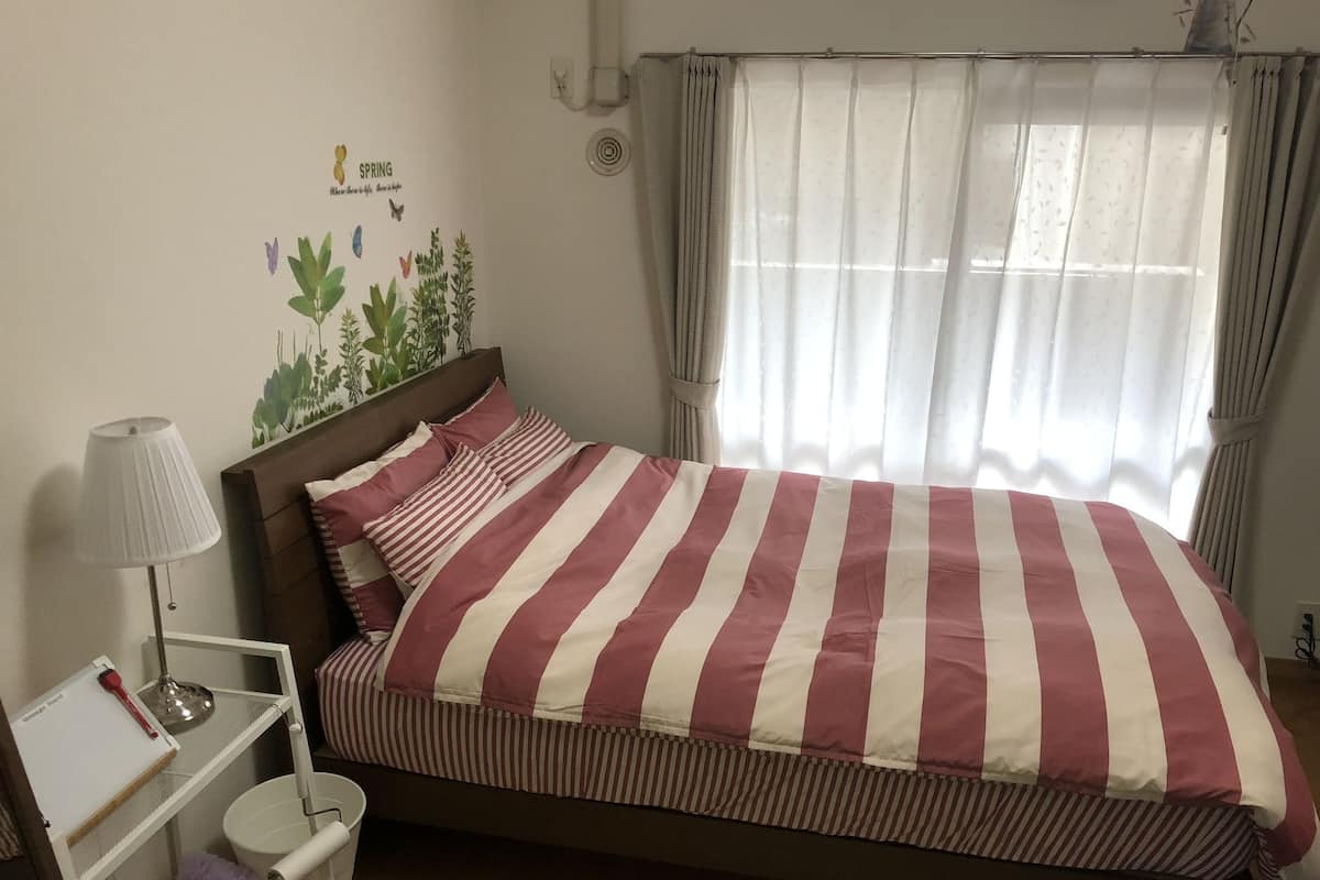 A neatly made bed with a striped bedspread, a bedside table with a lamp, and a wall decoration.