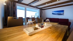 A dining area with a wooden table, chairs, and a red sofa. - Apartment THE GOOD VIEW I - Lake & Mountain view (Zell am See)
