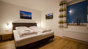 A neatly made double bed with white linens, a wooden headboard, and a nightstand with a lamp. - Apartment THE GOOD VIEW I - Lake & Mountain view (Zell am See)