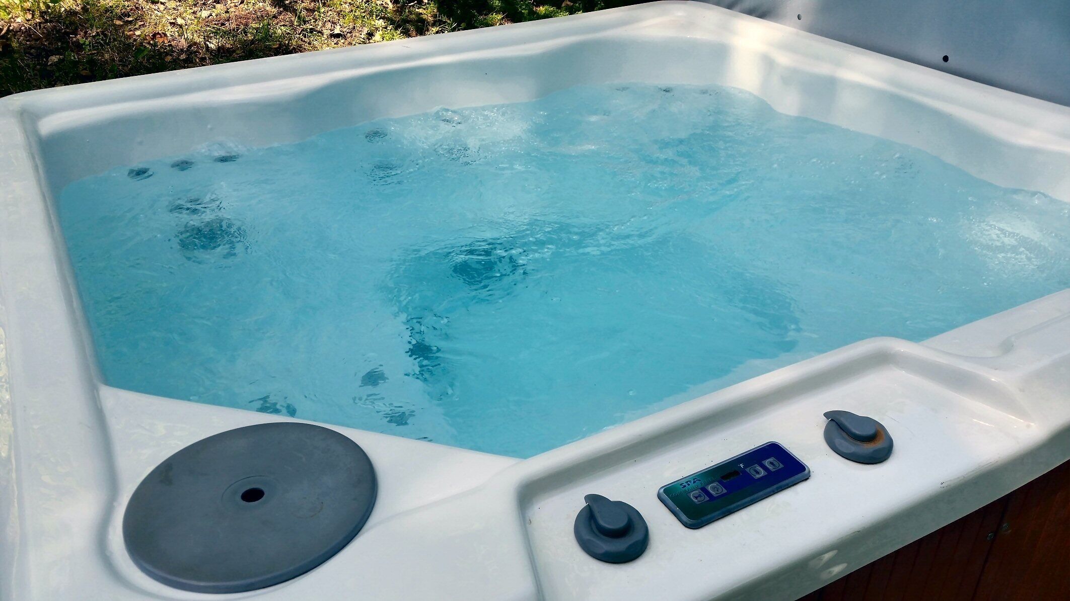 Un bain à remous doté d’un panneau de commande et d’un couvercle de vidange.