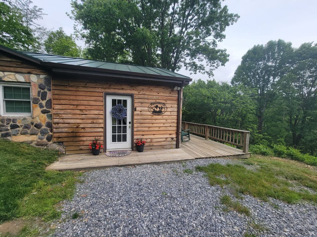 Une cabane rustique avec des fondations en pierre, un revêtement extérieur en bois et une terrasse en bois.