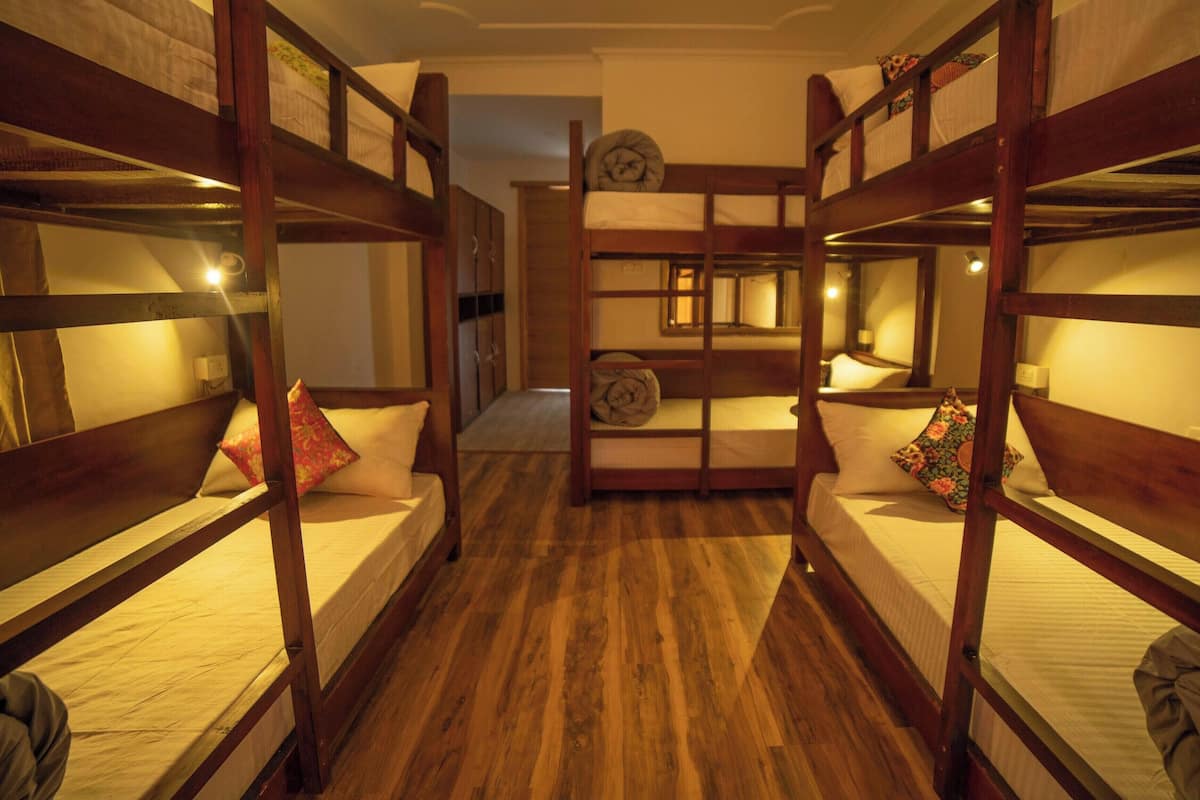 Quarto com beliches, piso de madeira e corredor que dá para outro quarto.