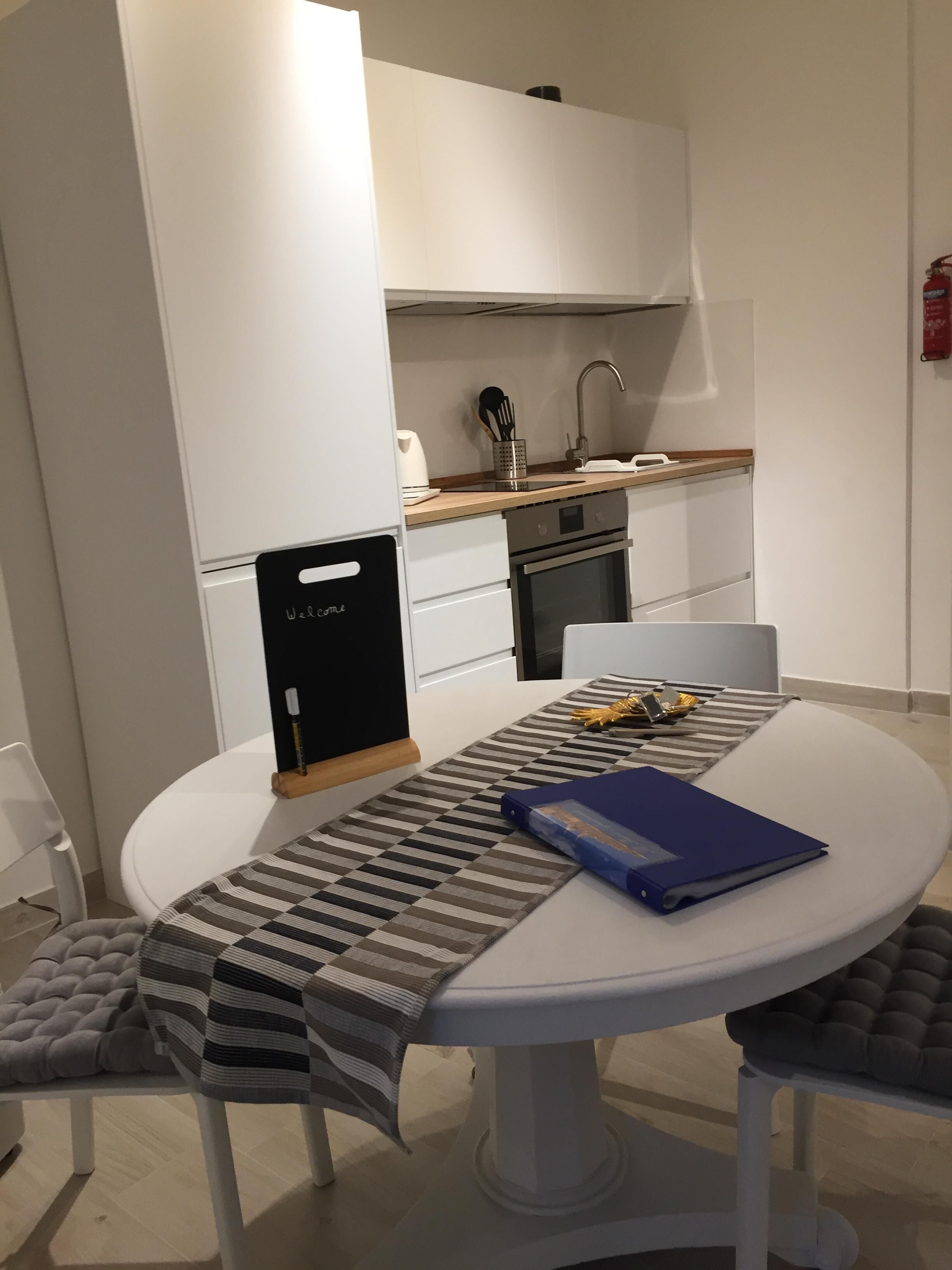 Une cuisine moderne avec des armoires blanches, des appareils en acier inoxydable et un plan de travail en bois.