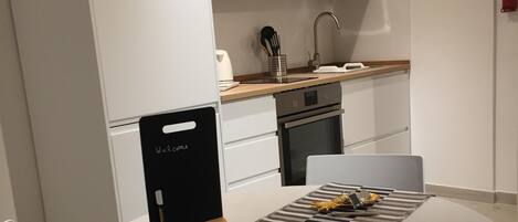 Une cuisine moderne avec des armoires blanches, des appareils en acier inoxydable et un plan de travail en bois.