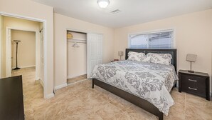 A bedroom with a bed, a nightstand, a lamp, a closet, and a door leading to another room. - 7 min from the strip with pool! (Las Vegas)
