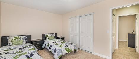 A bedroom with two beds, a closet, and a bathroom visible through an open door.