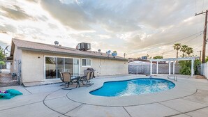 A backyard with a swimming pool, patio furniture, and a covered area. - 7 min from the strip with pool! (Las Vegas)