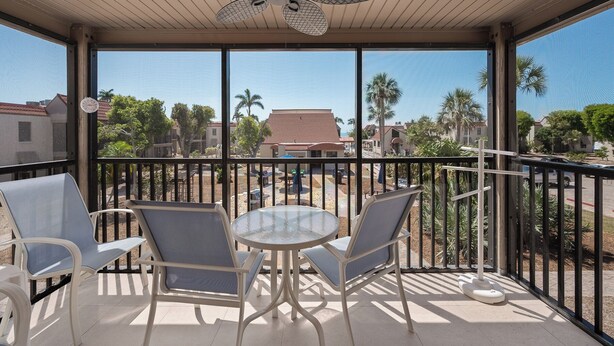 A covered outdoor seating area with a ceiling fan, two chairs, and a small table. - Tropical Garden View 2 bed, 2 bath at Sanibel Moorings #622 (Sanibel)