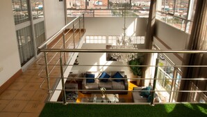 A spacious living area with a balcony, large windows, and a chandelier. - APARTAMENTO PENTHOUSE  DE 350 M2, CON VISTA PANORAMICA DE LA CIUDAD. (Cusco)
