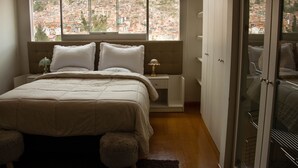 A bedroom with a large window, a bed with a headboard, a nightstand, and a wardrobe. - APARTAMENTO PENTHOUSE  DE 350 M2, CON VISTA PANORAMICA DE LA CIUDAD. (Cusco)