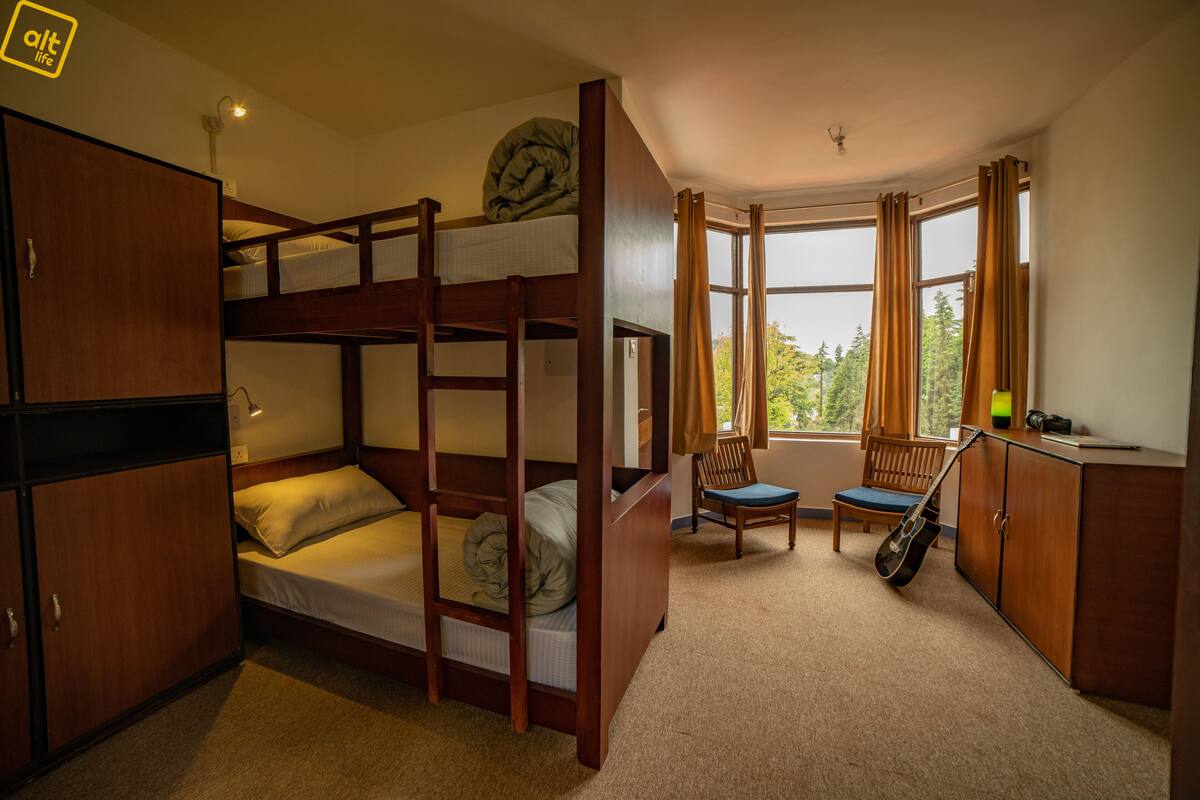 A bunk bed room with a desk, chair, and guitar.