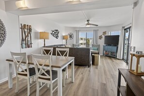 Una sala de estar moderna con comedor, ventilador de techo y televisor.