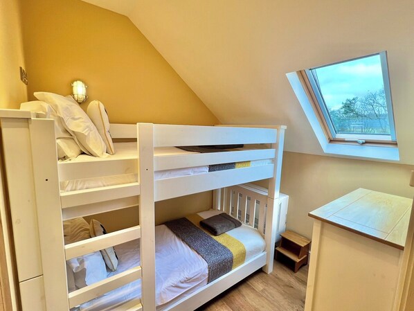 A bunk bed with a desk and a window in a room with a sloped ceiling. - Hastings Barn at High Park, Indoor Pool (Devon)