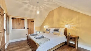 Um quarto com cama de madeira, mesa de cabeceira, abajur e luz no teto.