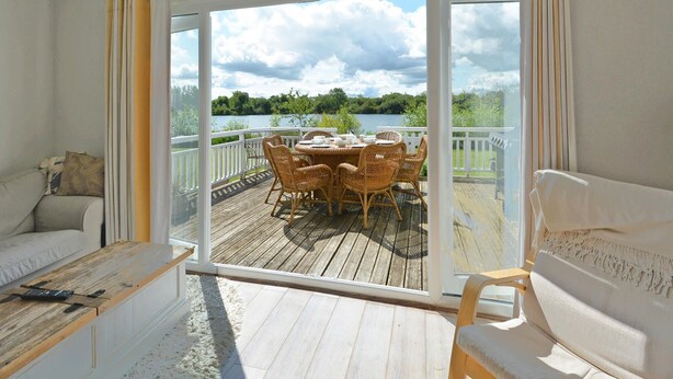 Una habitación con puerta corrediza de vidrio que da a una terraza exterior con mesa y sillas.