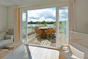 A room with a sliding glass door leading to an outdoor deck with a table and chairs. - Stylish New England lakeside retreat in the Cotswold Water Park (Cirencester)