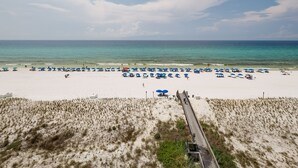 A beach with a wooden boardwalk leading to the water, sandy dunes, and beach umbrellas. - IBR 7008: Memories by the Sea - Where Dreams Meet the Ocean! (Fort Walton Beach)