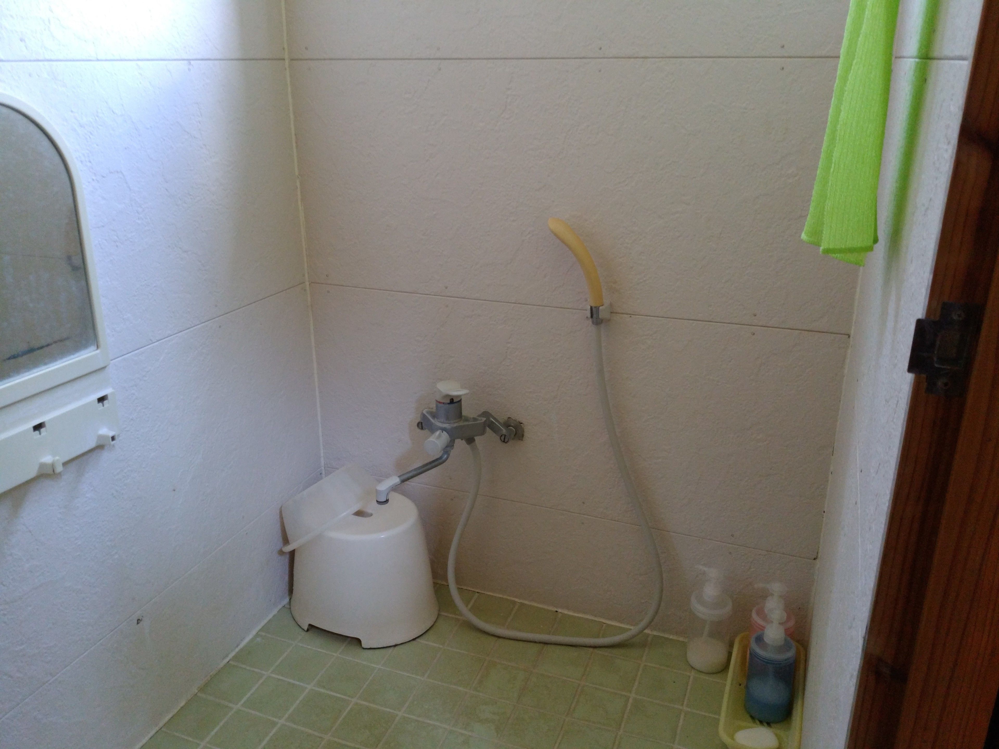 A small bathroom with a shower, a toilet, and a window.