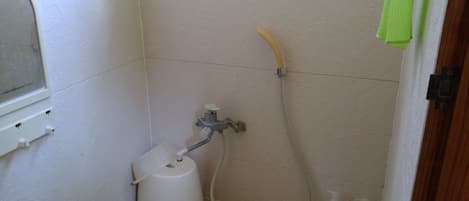 A small bathroom with a shower, a toilet, and a window.