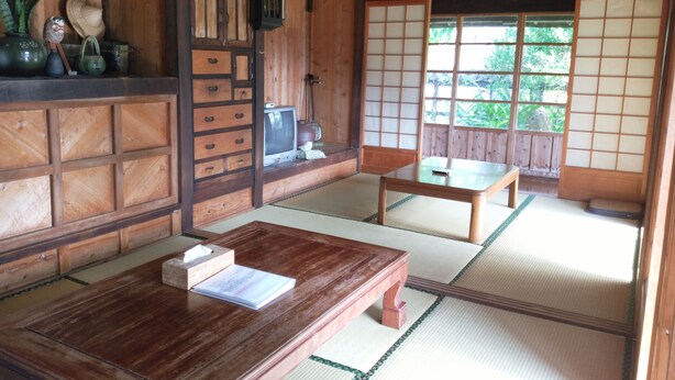 A traditional Japanese room with tatami flooring, a low wooden table, a television, and sliding shoji doors. - Cottage CANAC (Motobu)
