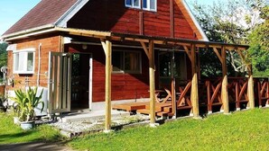 A wooden house with a pitched roof and a covered porch. - Cottage CANAC (Motobu)