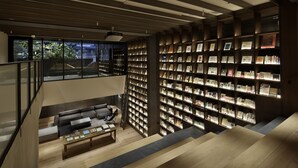 Eine moderne Bibliothek mit Bücherregalen, einem Sofa und einer Treppe.