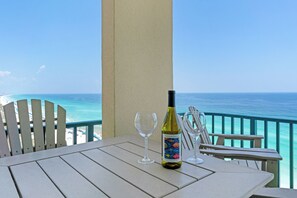 Ein Tisch mit einer Weinflasche und zwei Gläsern auf einem Balkon mit Blick auf den Ozean.