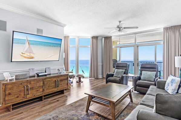 Ein geräumiges Wohnzimmer mit großem Flachbildfernseher, Holzmöbeln und Blick auf den Ozean.