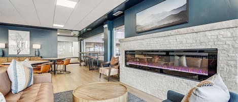 A modern lounge area with a fireplace, comfortable seating, and a view of the city.