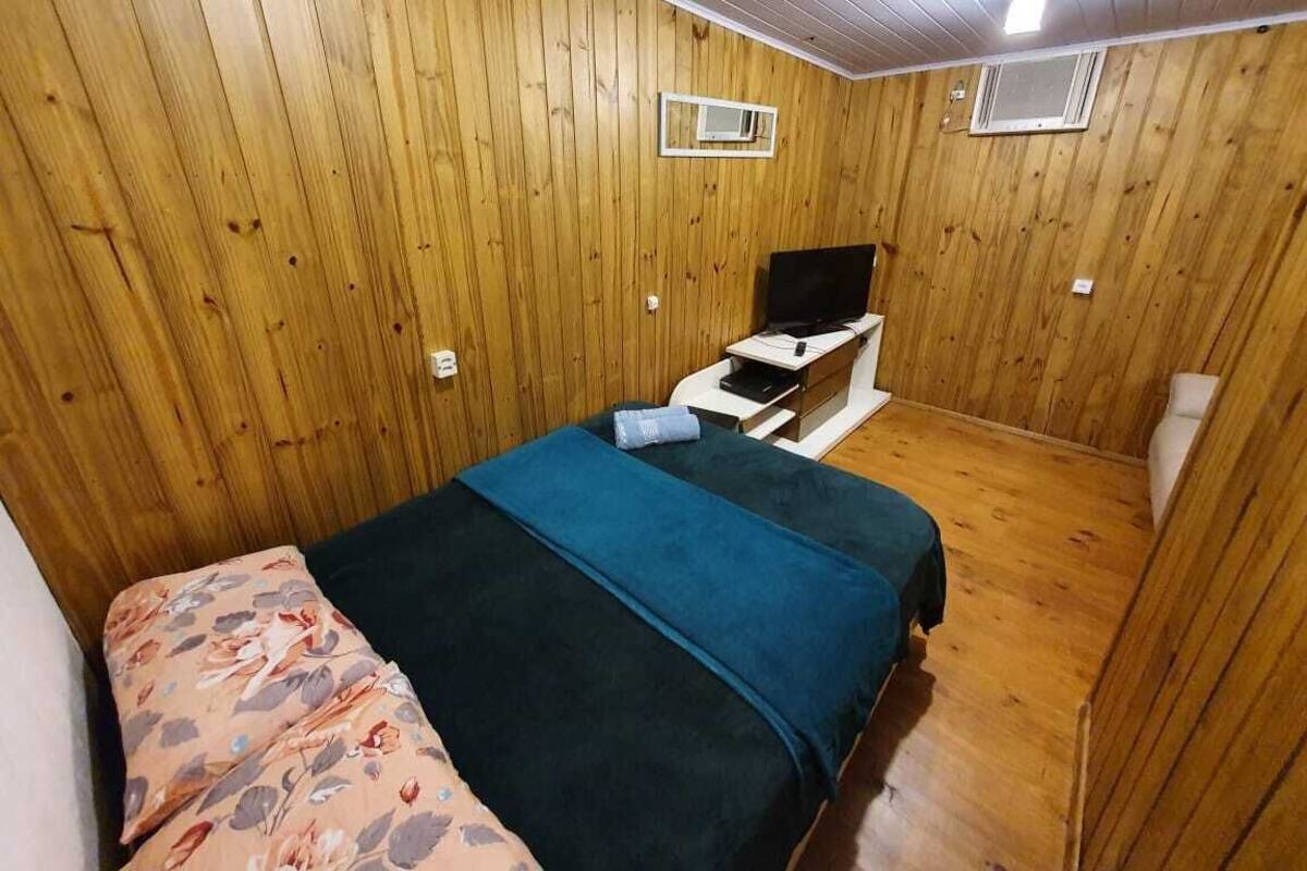 A wooden-paneled room with a bed, a small table, and a television.