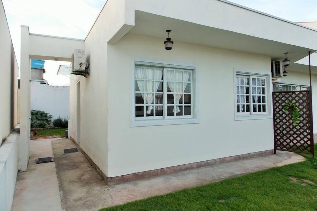 A modern single-story house with a flat roof, white exterior walls, and a small front yard.