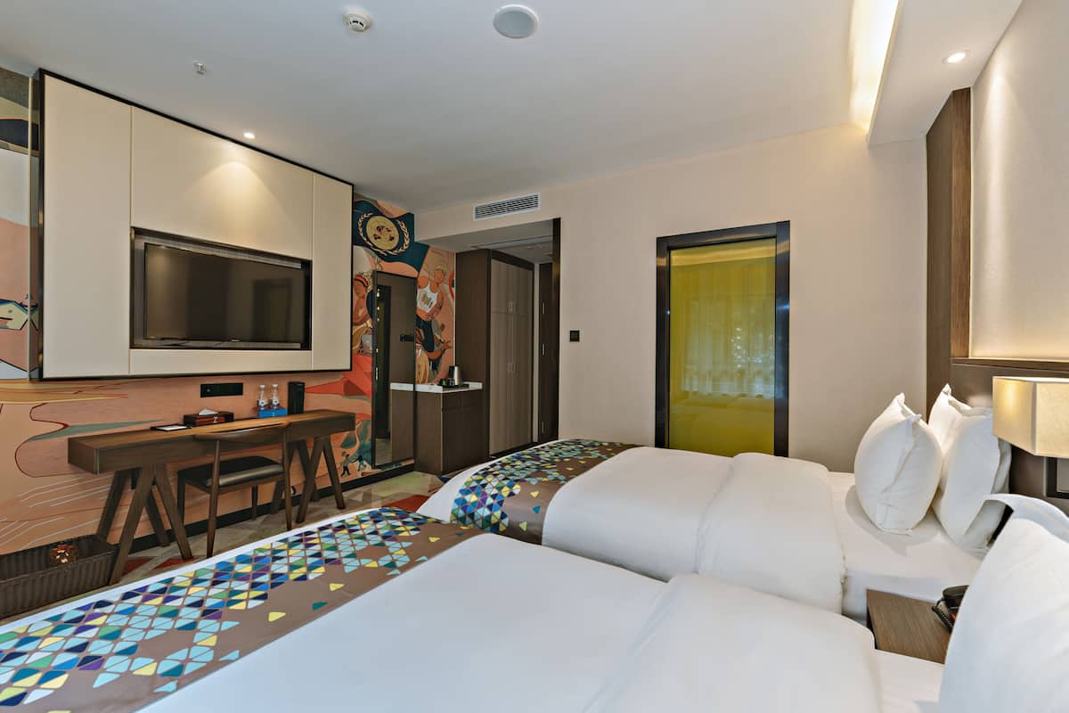 A hotel room with a bed, a desk with a chair, a television, and a bathroom door.