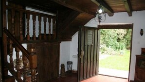 A wooden staircase leading to a room with a tiled floor and a door opening to a garden.