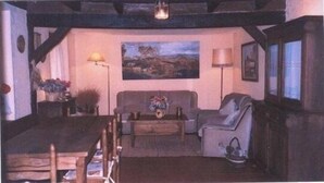 A cozy living room with a sofa, armchairs, a coffee table, and a painting on the wall.
