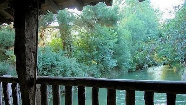 A wooden deck overlooking a river with dense greenery and trees.