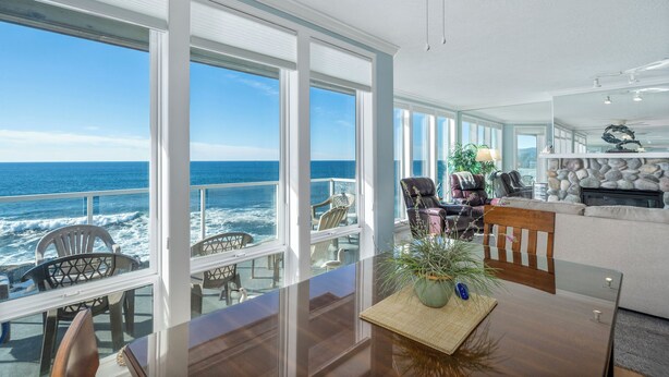 A spacious living area with large windows overlooking the ocean, a cozy seating area, and a fireplace. - Promo! Three Bedroom Oceanfront Condo, Wifi, HDTV, Hot Tub and Indoor Pool (Depoe Bay)