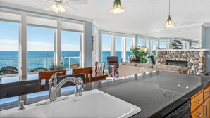A spacious kitchen with a large island, a stone fireplace, and a view of the ocean. - Promo! Three Bedroom Oceanfront Condo, Wifi, HDTV, Hot Tub and Indoor Pool (Depoe Bay)