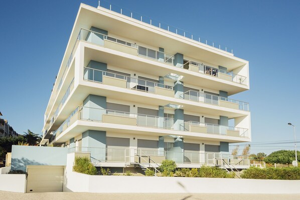 A multi-story building with balconies, a garage, and a clear sky.