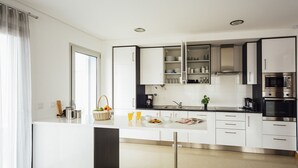 A modern kitchen with white cabinetry, stainless steel appliances, and a central island with breakfast items. - Clérigo - T2 Holiday Apartment in São Martinho do Porto By SCH (São Martinho do Porto)