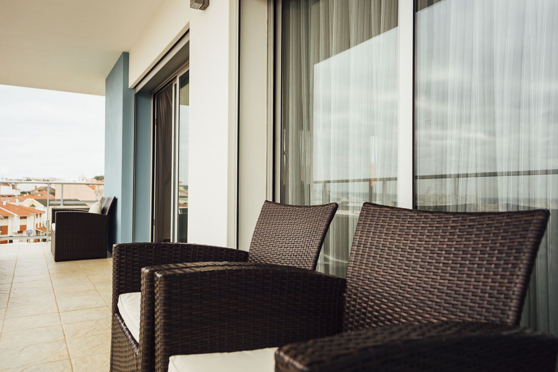 A balcony with wicker chairs and a view of buildings.