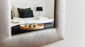 A hotel room with a neatly made bed, a bedside table with a lamp, and a tray with two cups and two pastries. - Clérigo - T2 Holiday Apartment in São Martinho do Porto By SCH (São Martinho do Porto)