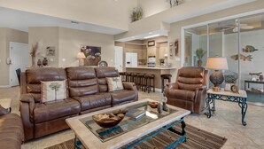 A spacious living room with leather sofas, a glass coffee table, and a kitchen in the background. - Wrap-Around Balcony, Two Swimming Pools, Walk to the Beach (Miramar Beach)