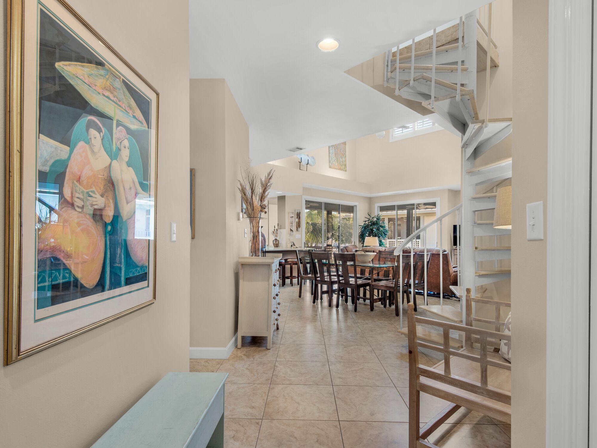 A spacious interior with a dining area, a staircase, and a large painting on the wall.