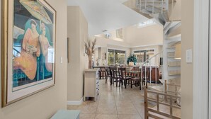 A spacious interior with a dining area, a staircase, and a large painting on the wall. - Wrap-Around Balcony, Two Swimming Pools, Walk to the Beach (Miramar Beach)