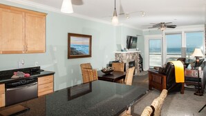 A kitchen with a dining area, a stone fireplace, and a view of the ocean.