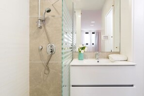 Ein modernes Badezimmer mit Duschkabine aus Glas, einem weißen Waschbecken und einem Spiegel.